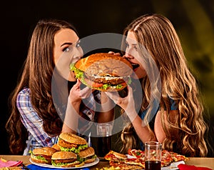 Women eating fast food. Gils eat hamburger with ham .