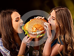 Women eating fast food. Gils eat hamburger with ham .