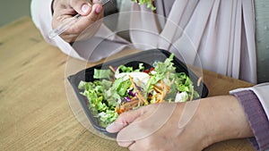 women eating fresh vegetable salad bowl on table,