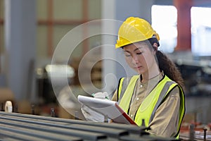 Women engineer take notes on paperwork quality control standing at machine.