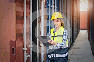 Women Engineer wears PPE checking container storage with cargo container background at sunset. Logistics global import or export