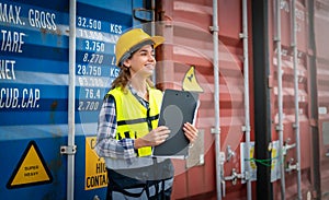 Women Engineer wears PPE checking container storage with cargo container background at sunset. Logistics global import or export