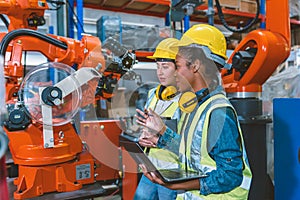 Women engineer worker working team training together at work in modern advanced robot welding machine factory