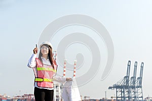 The women engineer working with container Cargo freight ship in shipyard at dusk