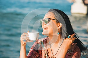 Women enjoying coffee time and summer wind at sunset time in a cafe overlooking the sea