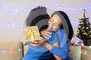 Women exchange gifts on the eve of the holiday. Black woman holding gift box with golden bow