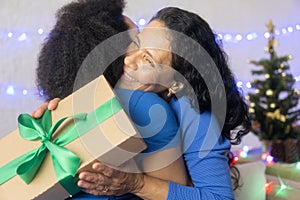 Women exchange gifts on the eve of the holiday. Black woman holding gift box with green bow