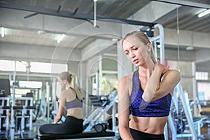 Women exercise already painful. Young caucasian female having pain in her neck while workout at the gym. Woman feeling strong pain