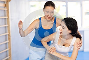 Women exercising armlock grip while sparring in sport gym