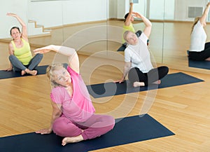 Women exercising during yoga class in fitness center - vakrasana pose photo