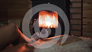 Women feet lie comfortably and warm by the warm fire of the fireplace