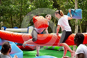 Women fighting by pillows on inflatable beam