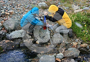 Women Filtering Water from Creek photo