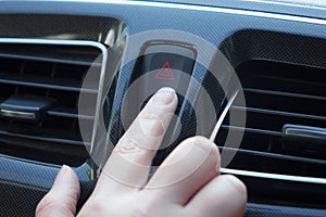 Women finger hitting car emergency red light button in car.