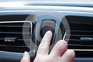 Women finger hitting car emergency red light button in car.