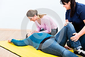 Women in first aid class training to position injured person