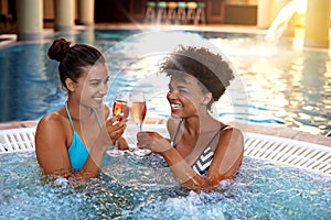 Women, friends and happy in jacuzzi with Champagne, self care and pamper day for wellness and cold beverage. Water photo