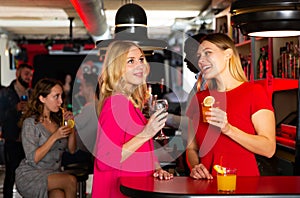 Women friends have fun and drinking cocktails on party in bar