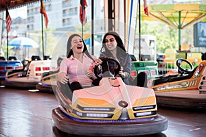 Women friends having fun at the amusement park, driving bumper car