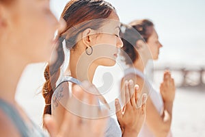 Women friends meditation while training yoga exercise on the beach. Group of zen female athlete working out outside with