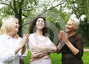 Women friends in the park celebrate a birthday. Clap your hands, congratulate, rejoice.