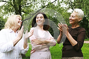Women friends in the park celebrate a birthday. Clap your hands, congratulate, rejoice. Happy summer day.
