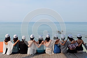 Women friends sit hug together backside look blue sea sky