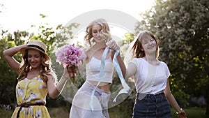 Women friendship. Three attractive girls in summer outfits. Holding hands together, walking playfully in the forest