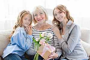 Women generation. Granny with presents, mom and daughter hugging grandmother