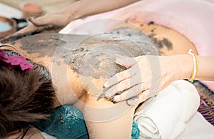 Women is getting Clay scrub on back in Spa