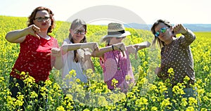 Women and girls showing thump down on a oilseed rape field - disappointment.