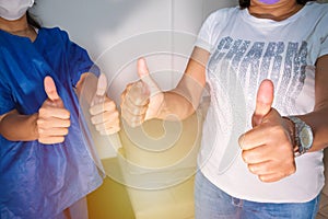 Women giving a victorious thumb to show their success and motivation, a close look at their raised hands