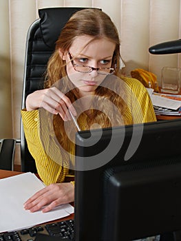Women in glasses is sitting by the computer
