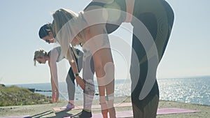 Women group practicing yoga doing dynamic asanas complex Vinyasa on sea shore.