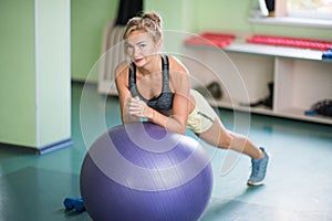 Women in gym with dumbbells doing exercise on the fit ball