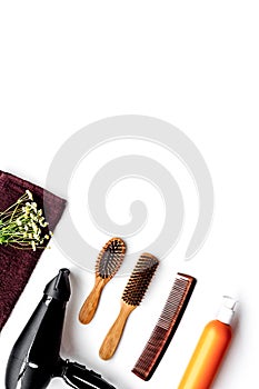 Women hair care set. Comb, shampoo, spray, curlers, hairdryer on white background top view copyspace