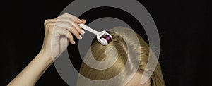 Women hair and mesoroller in hand on a black background. Care for the scalp, healthy hair