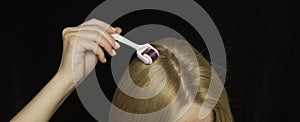 Women hair and mesoroller in hand on a black background. Care for the scalp, healthy hair photo