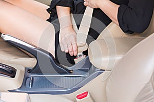 Women hand fastening seat belt inside car.
