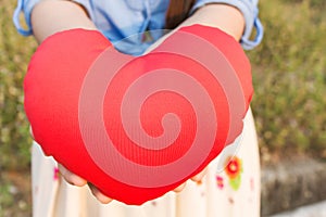 Women hand gently hold red heart with love, careness and restpect with copy sapce