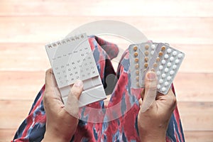 women hand golding birth control pills and calendar