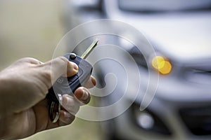 Women hand hand holding contactless car key and pressing the button on the remote to lock or unlock the car