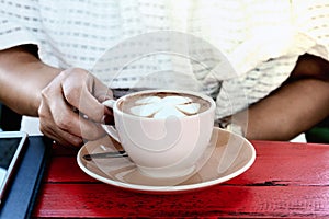 Women hand handle coffee cup in coffee shop