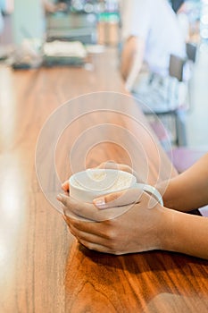 Women hand handle cup of hot coffee on wood table