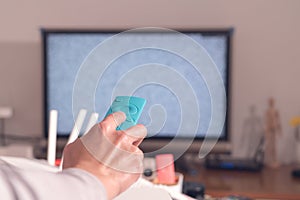 A women hand hold the remote control of the TV box in the living room, the blank screen TV