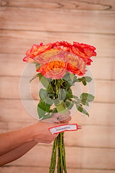 Women hand holding a bouquet of Free Spirit roses variety, studio shot, orange flowers