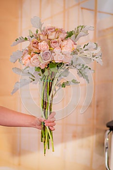 Women hand holding a bouquet of Pink roses and green foliage variety, studio shot, pink flowers