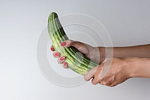 Women hand holding cucumber like a man`s penis on white background. Erotic concept