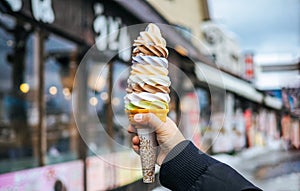 A women hand holding mixed colorful tasty ice cream soft cream cone with blurred shop background