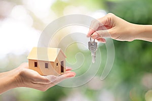 Women hand holding a model home and a key, Buying a new house con